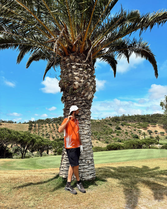 Golfer standing in front of date palm on Portuguese golf course wearing Volpe polo