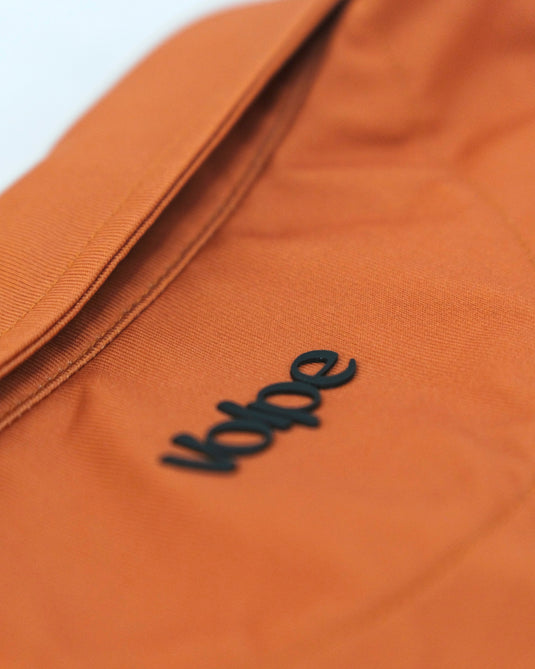 Close up of a logo on the back of a rust Volpe polo